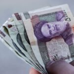 Detailed view of Iranian rial banknotes held in hand, illustrating finance and economy in Iran.