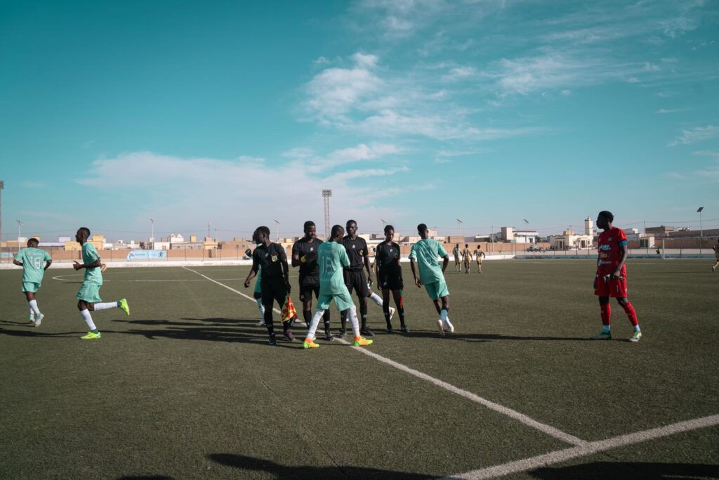 A group of male soccer players on a field during a sunny day game.