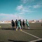 A group of male soccer players on a field during a sunny day game.