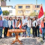 People standing together outdoors with Chilean and Peruvian flags in Tacna, Peru.