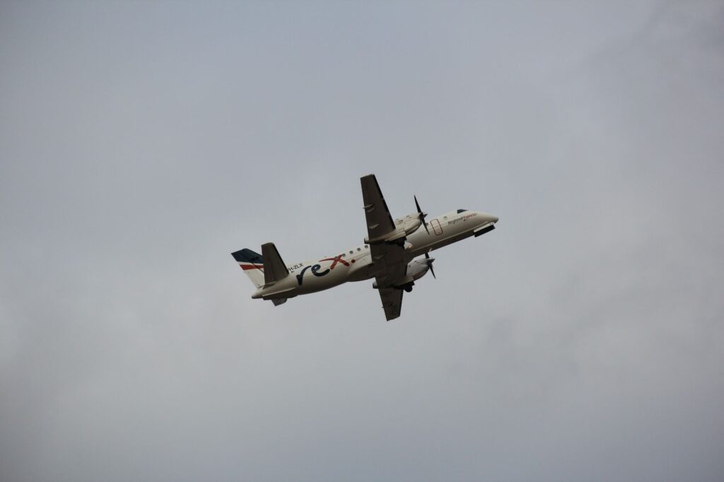 Rex Airlines Saab 340B captured soaring through cloudy skies above Melbourne Airport, Victoria.