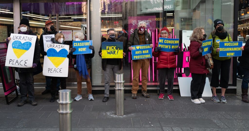 Protesters in New York holding signs advocating for peace and anti-war movements.