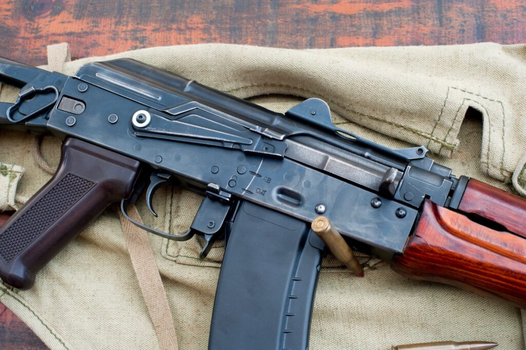 A detailed view of a military rifle with ammunition on a canvas backdrop.