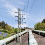 Industrial landscape with transmission tower, pipelines, and solar panels in Geesthacht, Germany.