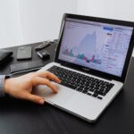 Person analyzing stock market data on a laptop at a desk.