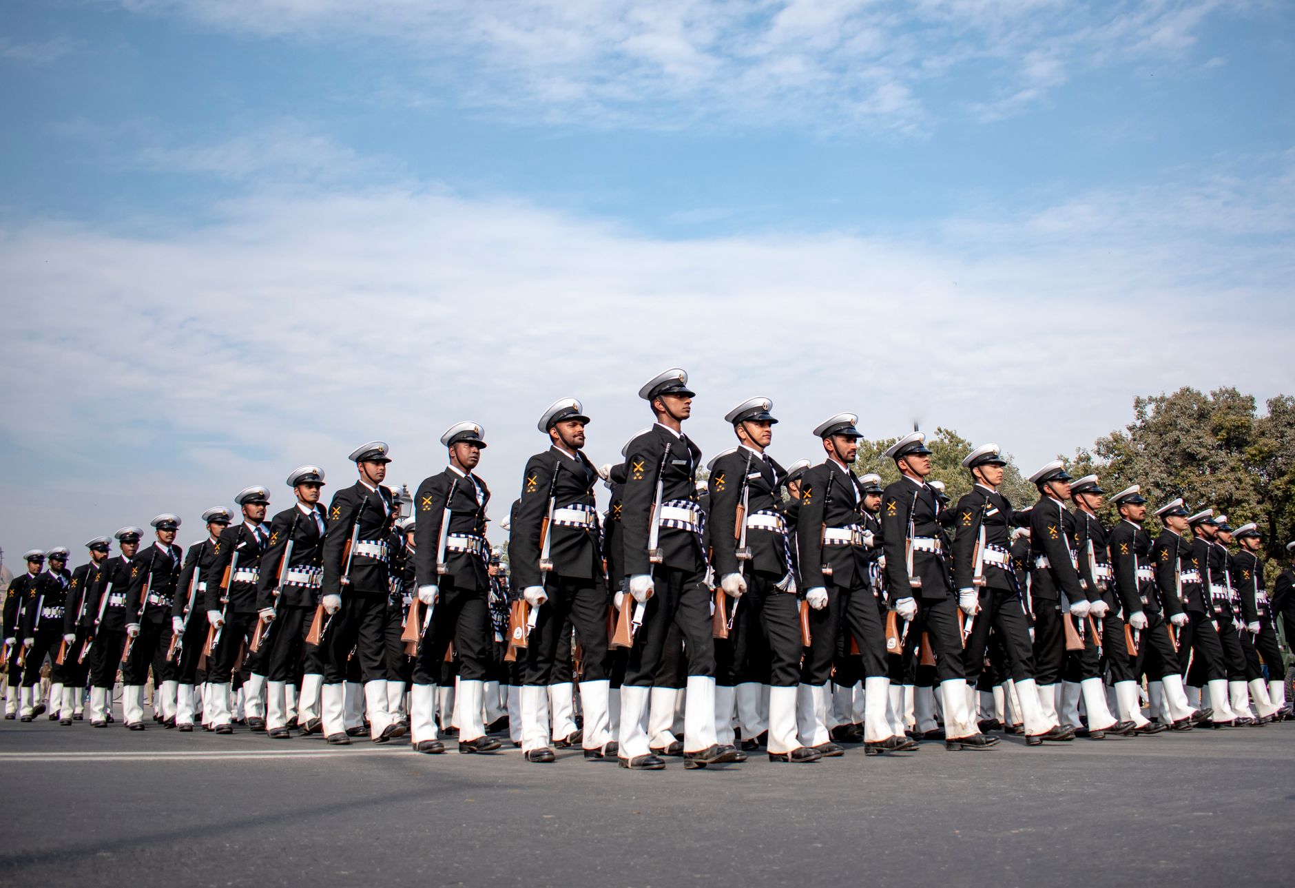 Indian naval officers in uniform marching in formation, showcasing discipline and unity during a parade in New Delhi.