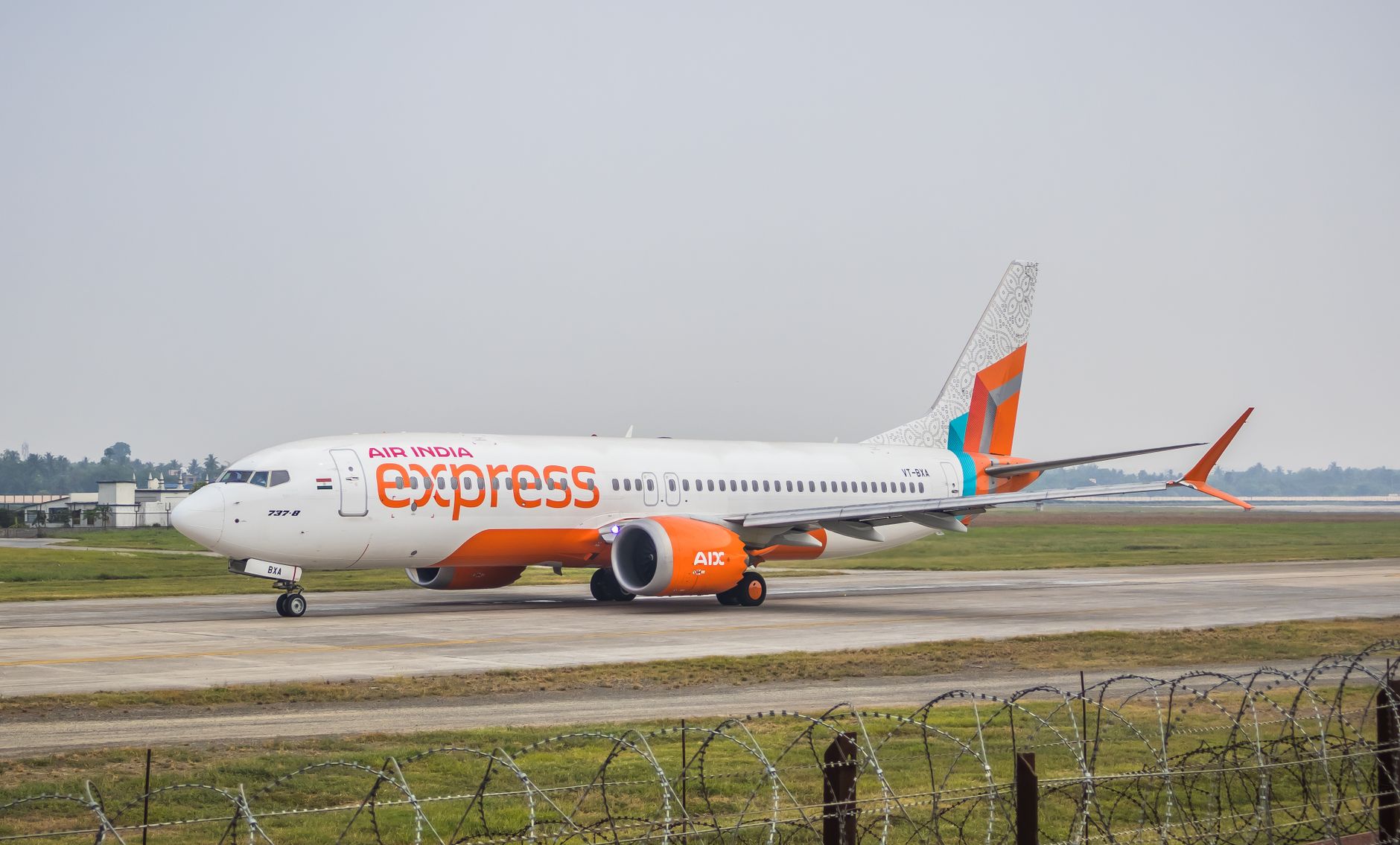 Air India Express plane on tarmac at airport, showcasing modern airplane design and branding.