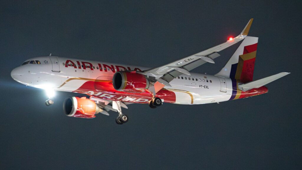 Air India Airbus A320 aircraft photographed during night flight with landing lights on.