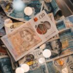 A detailed view of British £5 and £10 pound sterling notes with coins, featuring warm bokeh effects.
