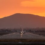 A cargo plane landing on a San Bernardino runway during sunset with mountains in the background.