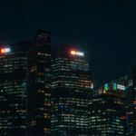 Illuminated city skyscrapers of major banks in Singapore's financial district at night.