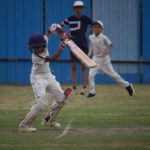 Young boys playing a competitive cricket match at Gahunje, showcasing teamwork.