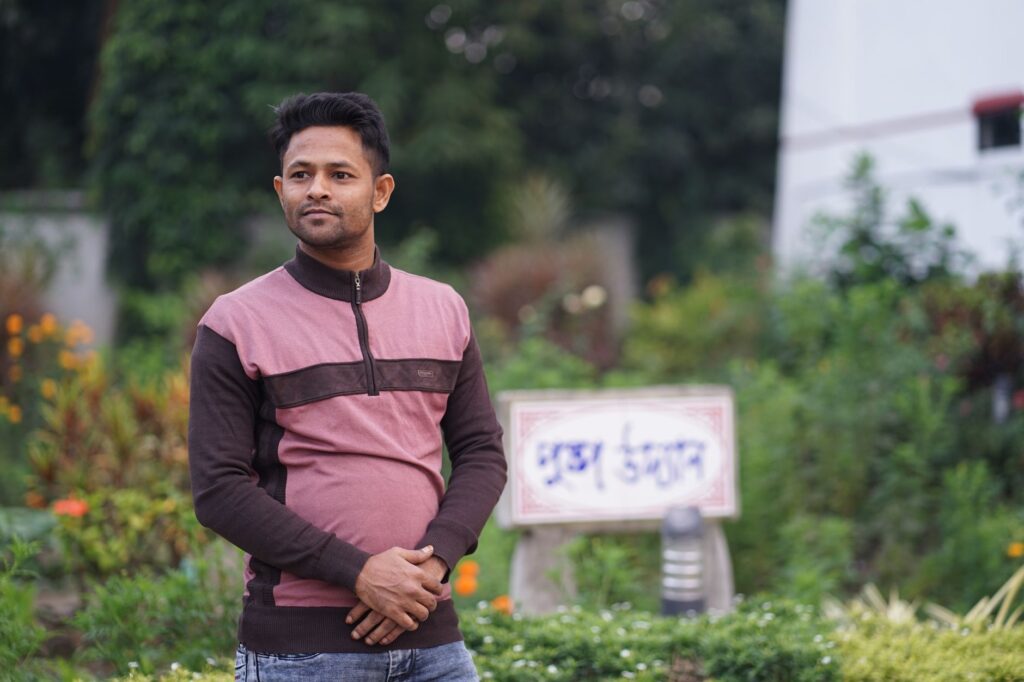 A man standing in a vibrant garden with various plants, exuding calmness and serenity.