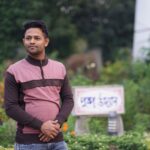 A man standing in a vibrant garden with various plants, exuding calmness and serenity.