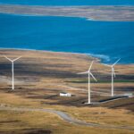 Aerial view of wind turbines on East Falkland near the ocean, showcasing sustainable energy in a natural landscape.