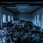 Interior of an abandoned building cluttered with trash and debris, creating a scene of decay and neglect.