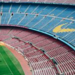 Aerial view of the empty Camp Nou stadium in Barcelona with colorful seats and green field.