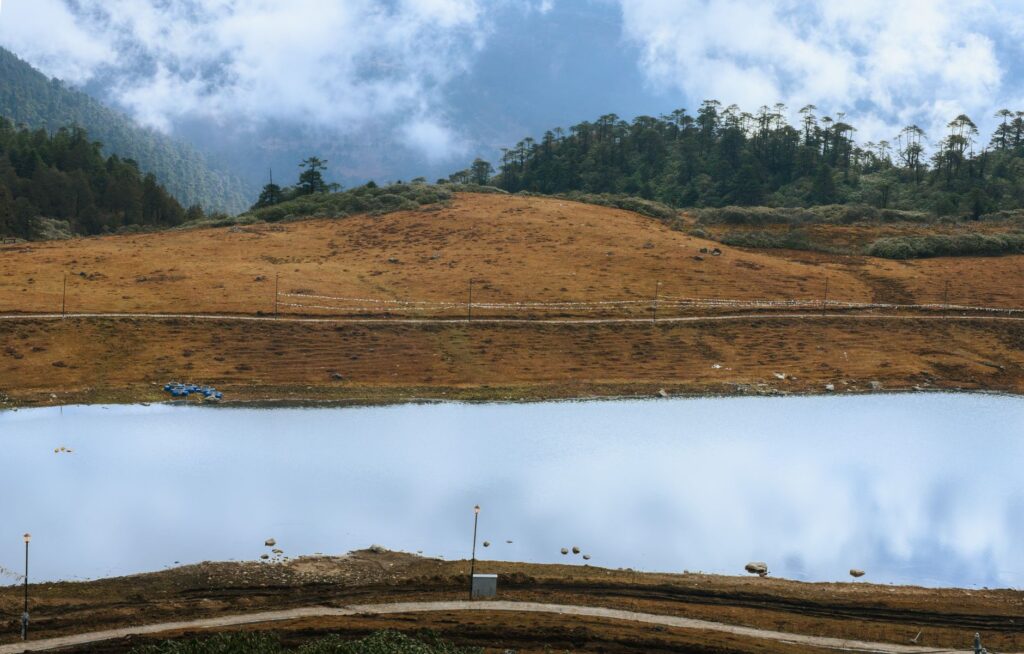 Serene landscape of a tranquil lake surrounded by lush forests in Arunachal Pradesh, India.
