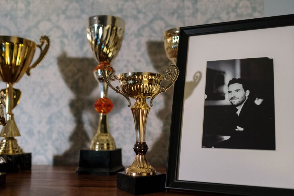 A collection of trophies with a framed black and white portrait on a shelf.
