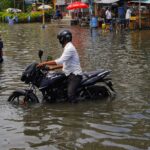 Motorcyclists navigate through a flooded street in Kolkata, India.