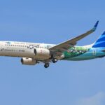 Garuda Indonesia Boeing 737 aircraft flying against a clear blue sky, showcasing vibrant livery.