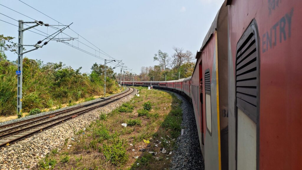 A train travels through the lush landscapes of Assam, India, showcasing the region's vibrant greenery.