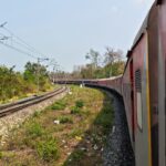 A train travels through the lush landscapes of Assam, India, showcasing the region's vibrant greenery.