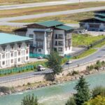 Scenic view of Bhutanese architecture along a river, capturing traditional design and natural beauty.