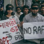A group of people protesting against sexual violence by holding signs and wearing blindfolds.