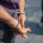 Close-up of an individual's hands in handcuffs, symbolizing arrest or crime.