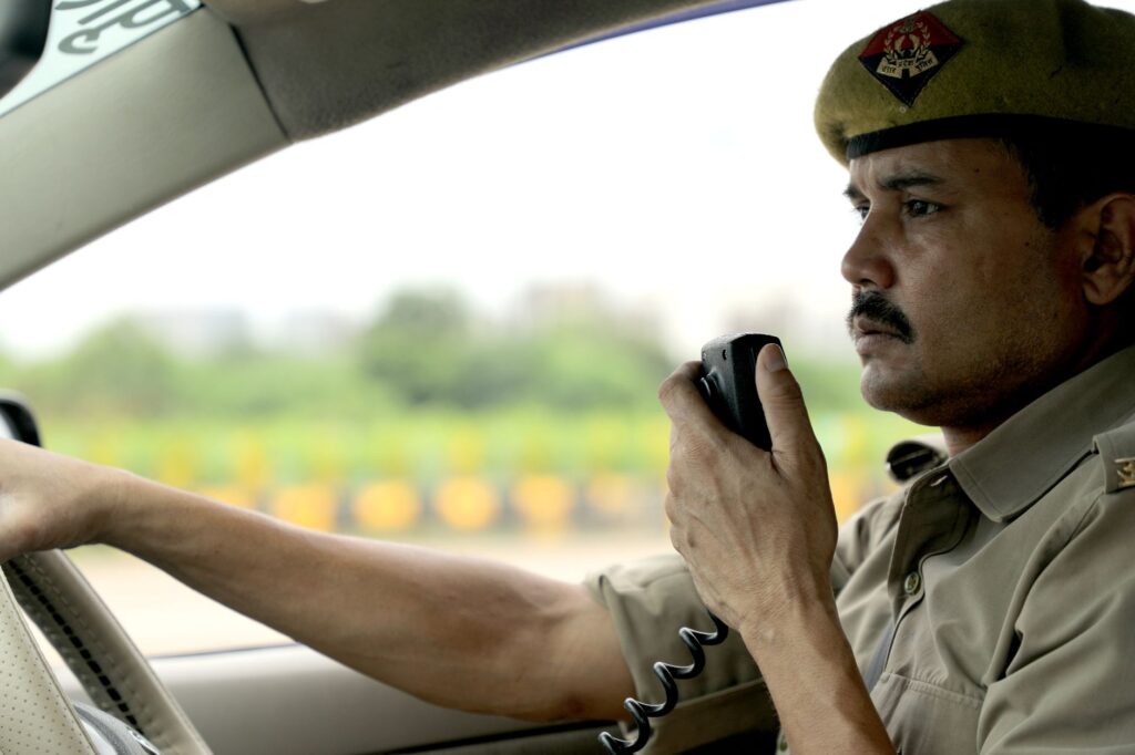 Police officer using a radio system while driving a patrol car, showcasing duty and focus.