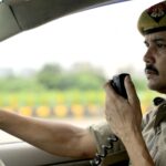 Police officer using a radio system while driving a patrol car, showcasing duty and focus.