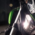 Detailed view of a sports motorcycle's illuminated headlight at night. Captures modern design.