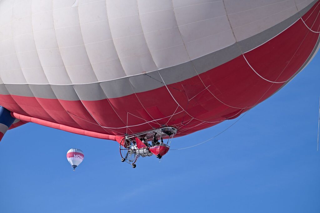 Colorful hot air balloon soaring in a clear blue sky during a vibrant festival in Château-d’Œx, Switzerland.