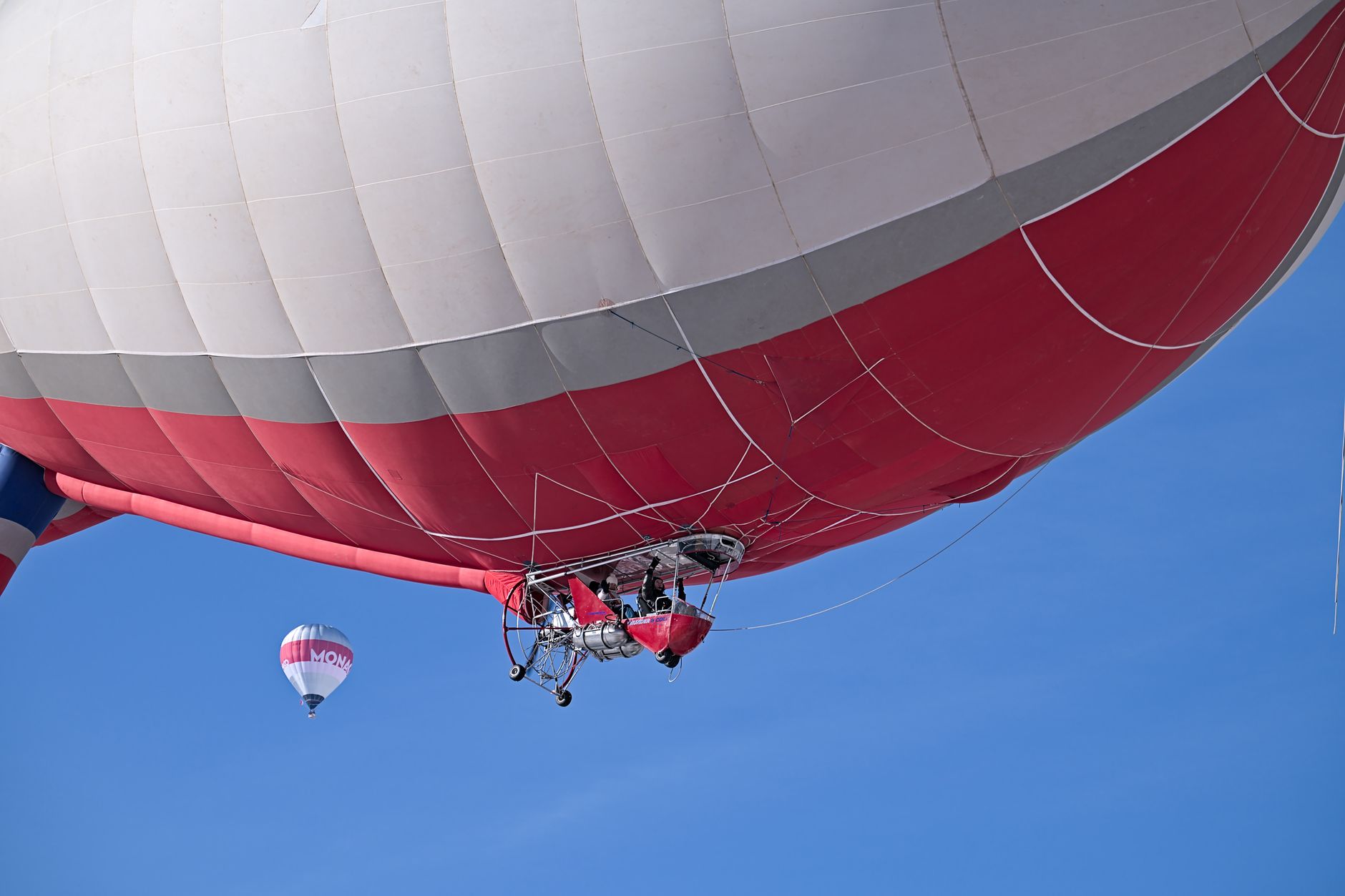 Colorful hot air balloon soaring in a clear blue sky during a vibrant festival in Château-d’Œx, Switzerland.