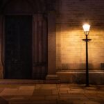 A dimly lit street lamp illuminates a medieval church entrance, creating an atmospheric night scene.