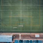 Aerial view of distant unrecognizable people standing on green grassy rugby field on sunny day