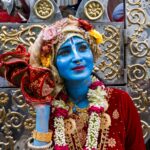A vibrant portrayal of a person dressed as Lord Krishna during a festival celebration in Dhaka, Bangladesh.