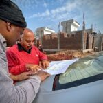 Team of architects examining building plans outdoors at a construction site.