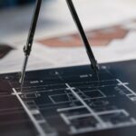 A compass on architectural blueprints, showcasing planning and measurement details.