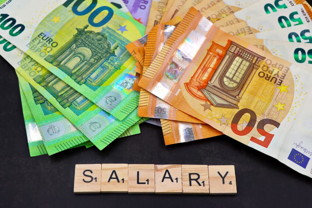 Euro banknotes alongside wooden Scrabble letters spelling 'salary' symbolize financial earnings and payroll.