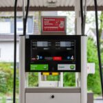 Close-up of a gas pump at a station in Bergisch Gladbach, Germany, with surrounding houses visible.
