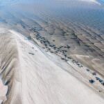 A stunning aerial capture revealing intricate sand patterns and cattle along a riverbank.