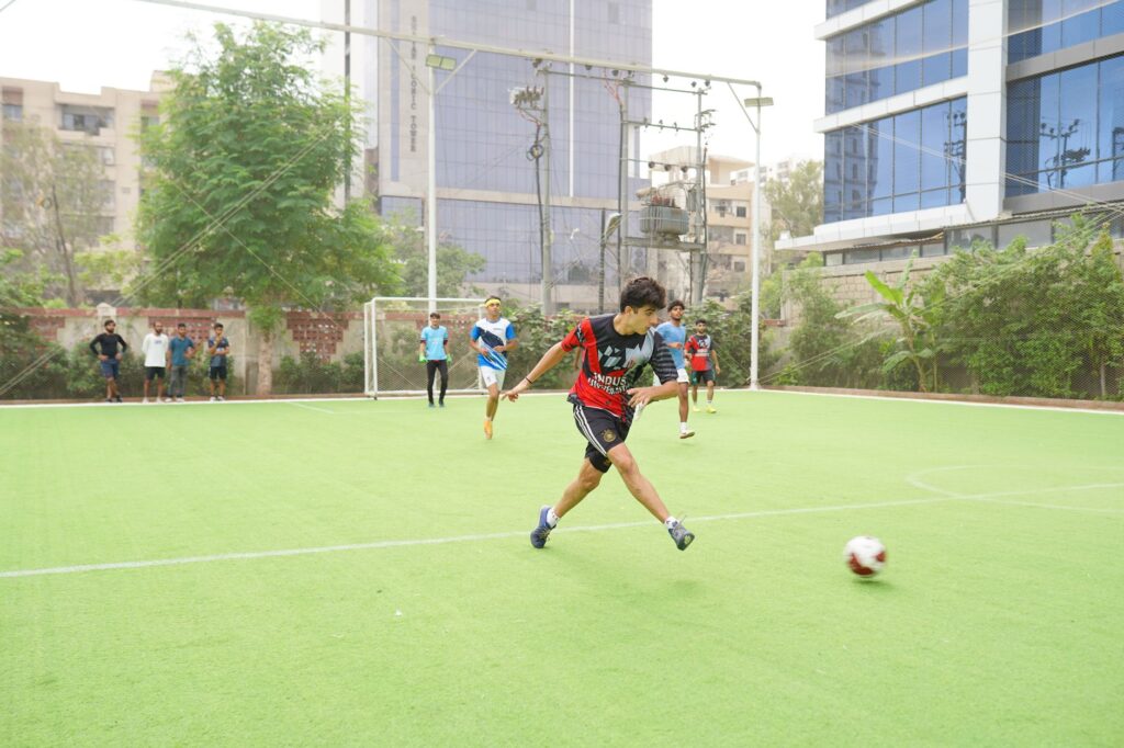 A young soccer player in action kicking the ball on an outdoor field surrounded by teammates.