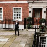 Man on phone near brick building in Grosvenor Square, London.