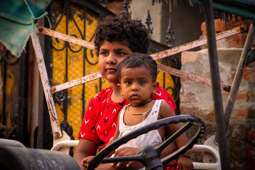 Two children sitting on a rickshaw in Rohtak, India displaying joy and innocence.