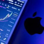 A close-up of an Apple device displaying stock market graphs, indicating economic trends.