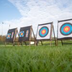 View of archery targets set up on a lush green field with a clear sky.