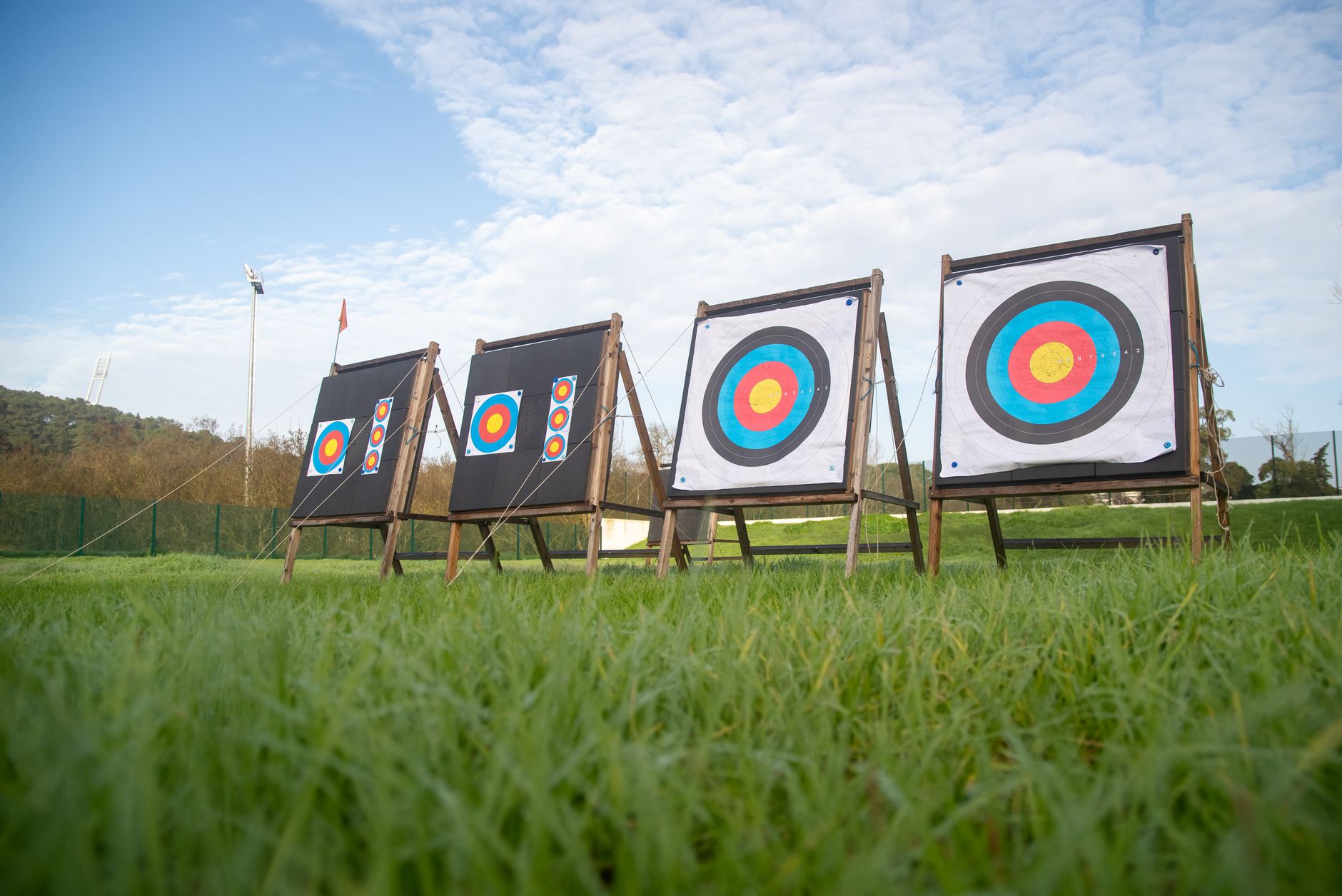 View of archery targets set up on a lush green field with a clear sky.