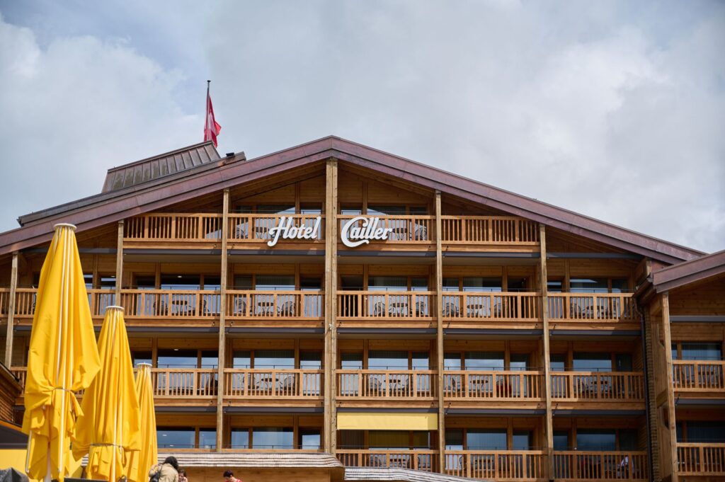 Rustic wooden architecture of Hotel Cailler with balconies and yellow umbrellas in Charmey, Switzerland.
